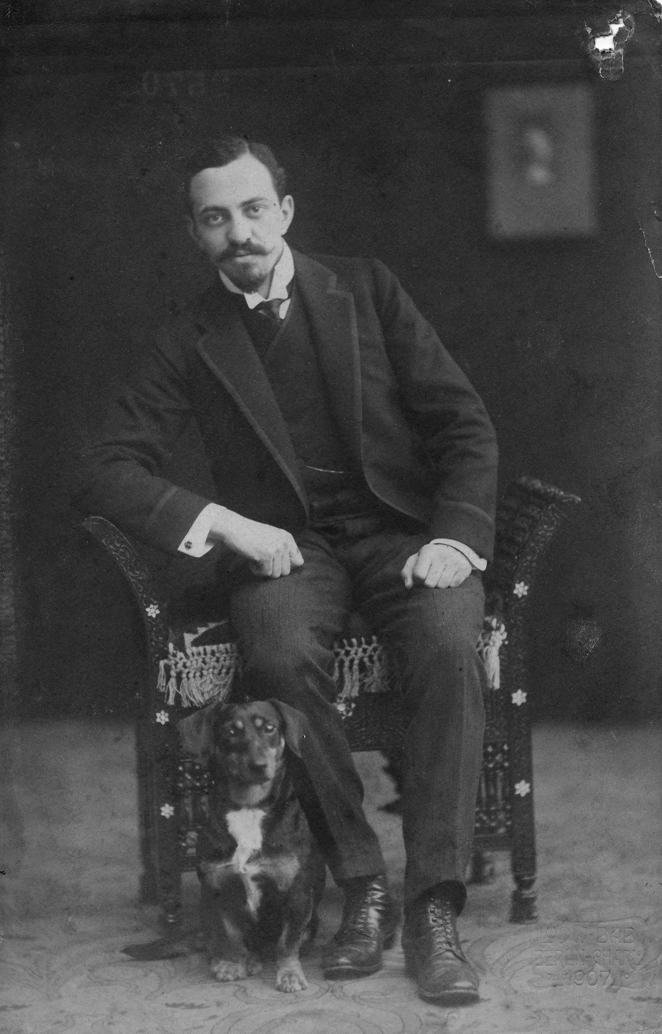 Portrait von Hugo Simon auf eine Stuhl sitzen mit kleinem Hund neben dem Bein